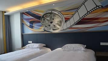 A hotel room with two beds, a large film reel mural on the wall, and a modern headboard.