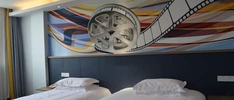 A hotel room with two beds, a large film reel mural on the wall, and a modern headboard.