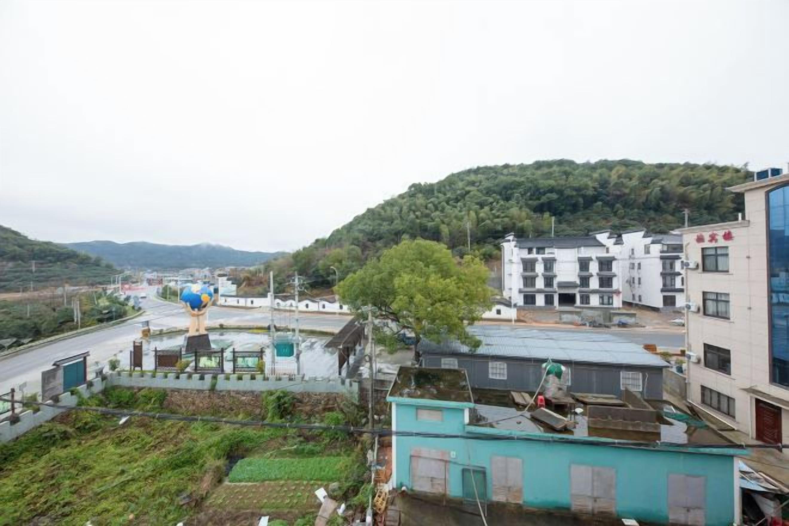 A residential area with buildings, a road, and a hill in the background.