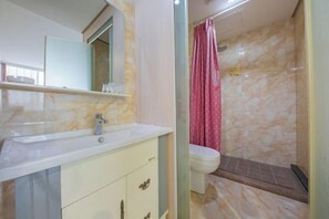 A bathroom with a marble sink, a mirror, a toilet, and a shower with a pink curtain. - Hong Xiang Hotel (Xiangshan)
