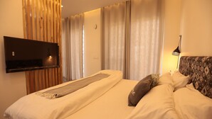 Habitación de hotel con una cama, un televisor montado en la pared y un cabecero estampado.