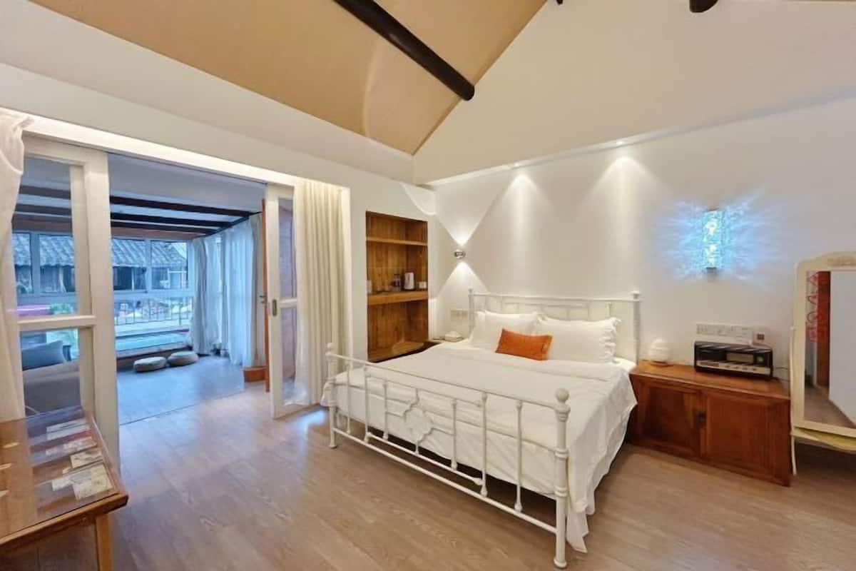 Ein Schlafzimmer mit einem weißen Metallbett, Holzregalen, einem Nachttisch und einer Deckenleuchte.