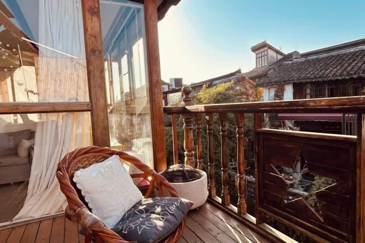 Eine Holzterrasse mit einem Korbstuhl und einem Blumentopf.