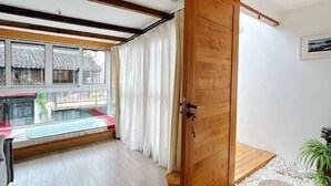 A room with a wooden door, a window with curtains, a small table, and a view of traditional buildings outside. - Yunlu Music Homestay (Zhujiajiao Scenic Area) (Shanghai)