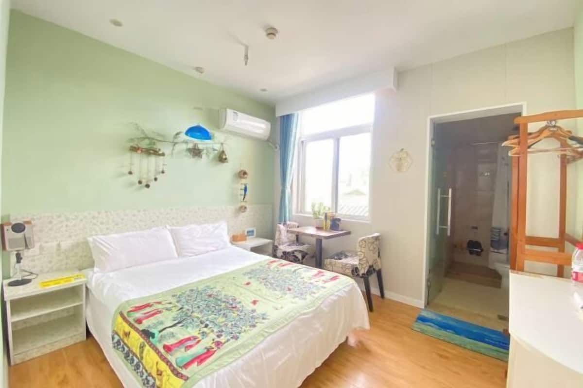 Ein Schlafzimmer mit einem Bett, einem Nachttisch, einem Sessel und einem Fenster.