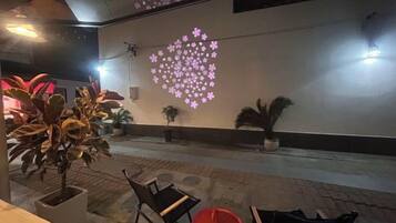 An indoor area with a wall-mounted projection of a heart-shaped pattern, potted plants, and seating arrangements.
