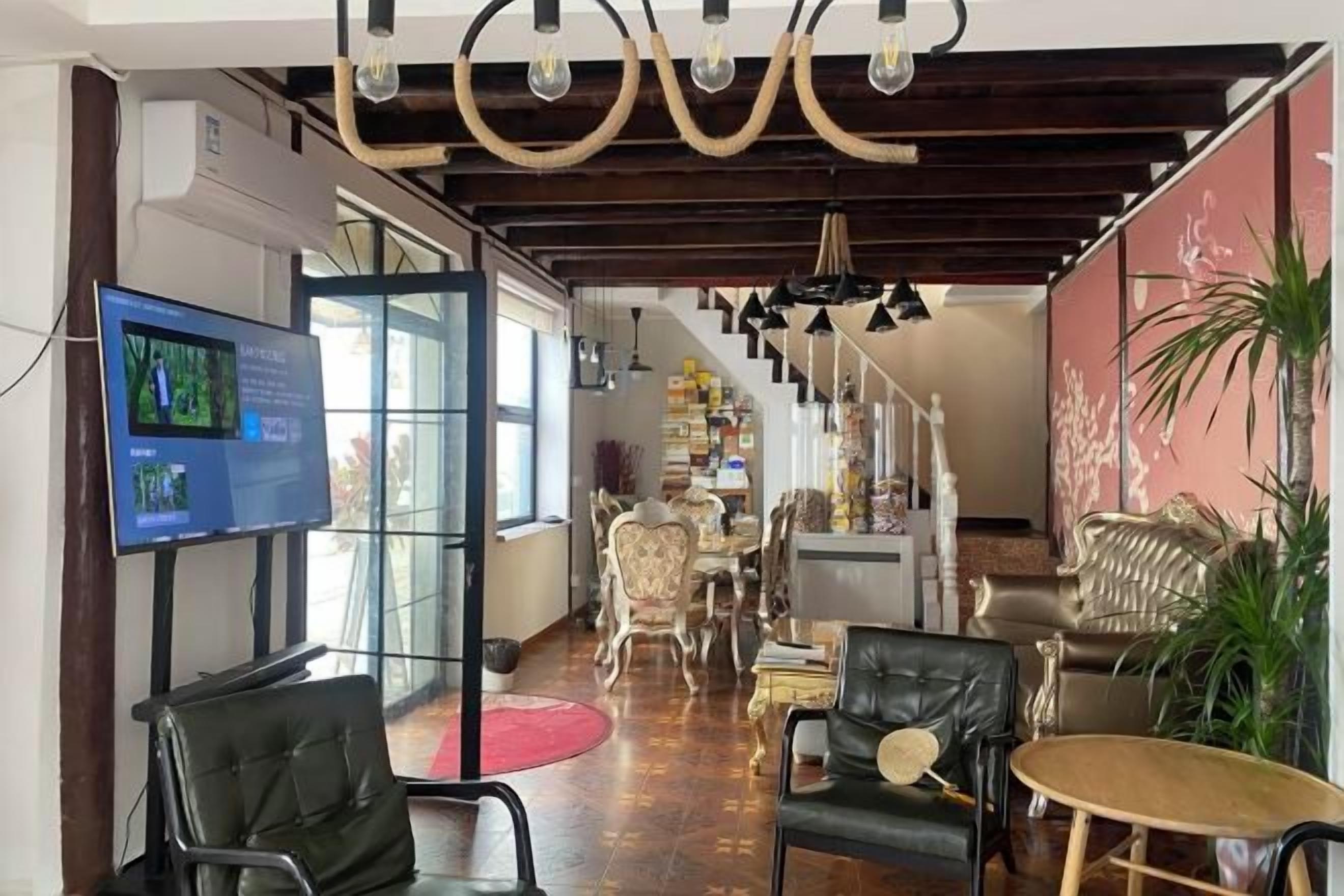 A hotel lobby with a television, seating area, and a staircase leading to upper floors.