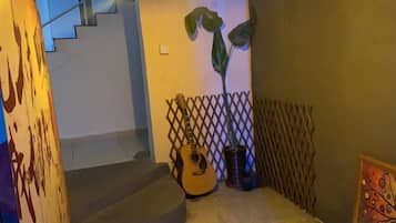Una escalera con una guitarra y una planta, que lleva a una habitación con un papel tapiz decorativo.