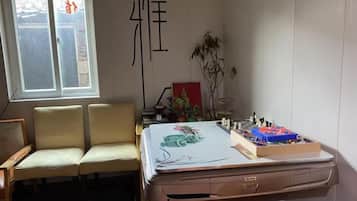 A room with a desk, two chairs, a window, and a decorative item on the wall.