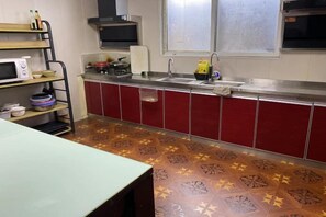 A kitchen with red cabinets, a microwave, and a patterned floor. - Yunlu Music Homestay (Zhujiajiao Scenic Area) (Shanghai)