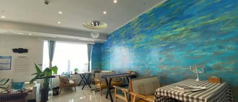 A dining area with a blue mural, a piano, and a table with a checkered tablecloth.