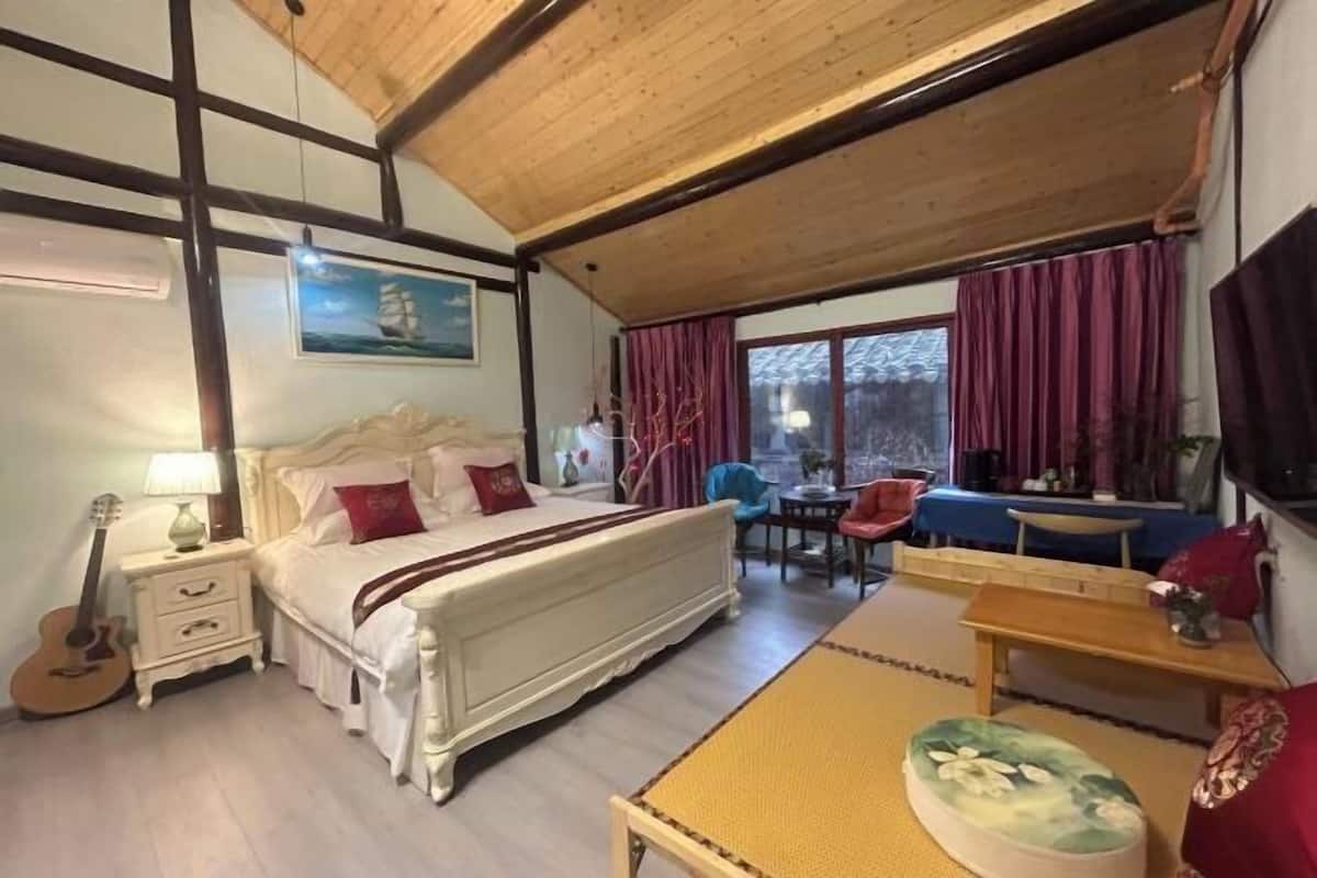 Ein Schlafzimmer mit Bett, Nachttisch, Lampe und einer Gitarre. Es gibt einen Essbereich mit Tisch und Stühlen.