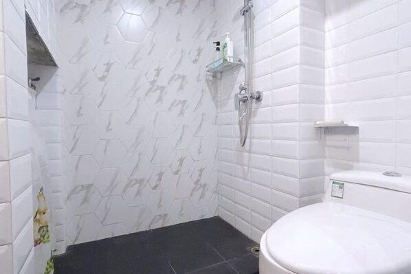 A bathroom with white hexagonal tiles, a shower, a toilet, and a shelf with toiletries. - Yunlu Music Homestay (Zhujiajiao Scenic Area) (Shanghai)