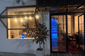 A hotel room with a large window, a potted plant, and a view of a traditional building. - Yunlu Music Homestay (Zhujiajiao Scenic Area) (Shanghai)