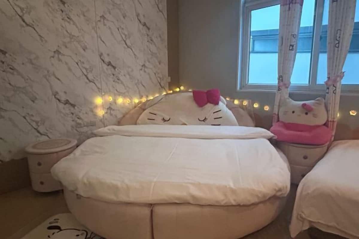Ein Schlafzimmer mit einem runden Bett, einem Nachttisch, einem Fenster mit Vorhängen und Lichterketten.