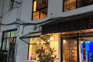 Un edificio con un balcón, una ventana con una planta y un letrero con texto.