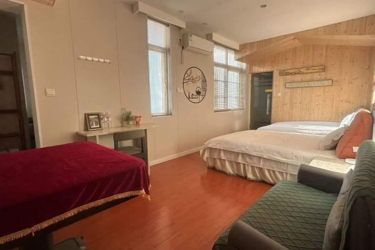 Ein Zimmer mit zwei Betten, einer Holzwand und einem kleinen Tisch mit roter Tischdecke.