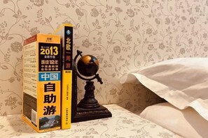 A bed with a floral-patterned wall and a globe on a stand beside a book titled "2013 China Travel Guide". - Yunlu Music Homestay (Zhujiajiao Scenic Area) (Shanghai)