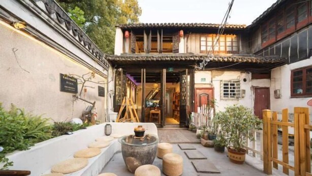 A traditional courtyard with a stone fountain, woven stools, and potted plants. - Yunlu Music Homestay (Zhujiajiao Scenic Area) (Shanghai)