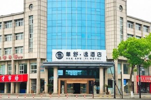 Un edificio moderno con un amplio frente de vidrio y un letrero que indica Hotel Hua Shu Yi.