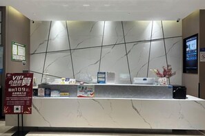 Balcão de recepção de hotel com bancada de mármore, tela digital e placa VIP.