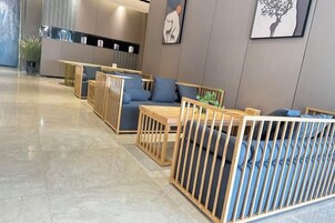 Un moderno vestíbulo de hotel con áreas de estar, un mostrador de recepción y un comedor.