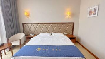 Ein Hotelzimmer mit Bett, Nachttischen, einem Sessel und Wandlampen.