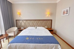 A hotel room with a bed, bedside tables, a chair, and wall-mounted lamps.