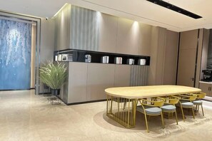 A modern kitchen with a wooden dining table and yellow chairs, a built-in black appliance, and a potted plant. - Huashu Yi Hotel (Pinghu Branch) (Pinghu)