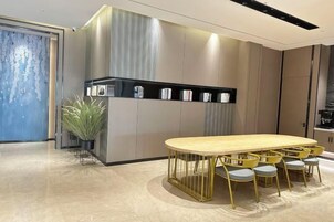 Una cocina moderna con una mesa de comedor de madera y sillas amarillas, un electrodoméstico negro empotrado y una planta en maceta.