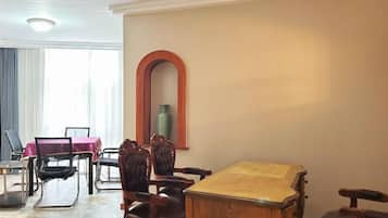 Un comedor con una mesa y sillas de madera, un espejo grande y un florero en la pared.