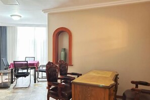 Un comedor con una mesa y sillas de madera, un espejo grande y un florero en la pared.