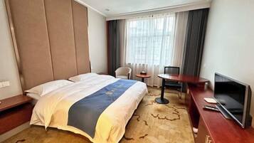 Ein Hotelzimmer mit Bett, Schreibtisch mit Fernseher, Stuhl und kleinem Tisch.