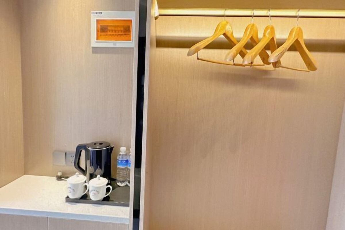 Una habitación de hotel con una cafetera, dos tazas y una botella de agua sobre la encimera.