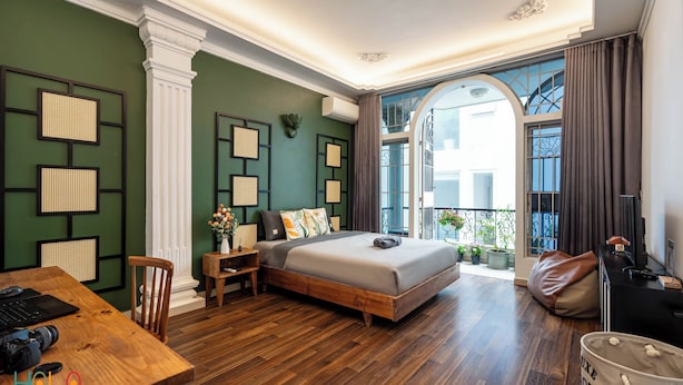 A modern bedroom with a wooden bed, a desk, and a balcony with a view. - New HoLo Le Thanh Ton SaiGon (Ho Chi Minh City)