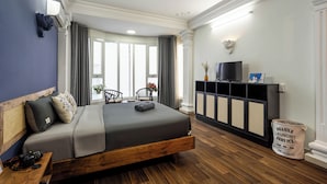 A modern hotel room with a large bed, a wooden headboard, a television, a minibar, and a view of the outdoors. - New HoLo Le Thanh Ton SaiGon (Ho Chi Minh City)