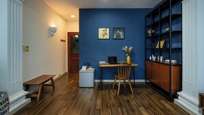A room with a wooden floor, a desk with a laptop, a chair, a bookshelf, and framed pictures on the wall. - New HoLo Le Thanh Ton SaiGon (Ho Chi Minh City)