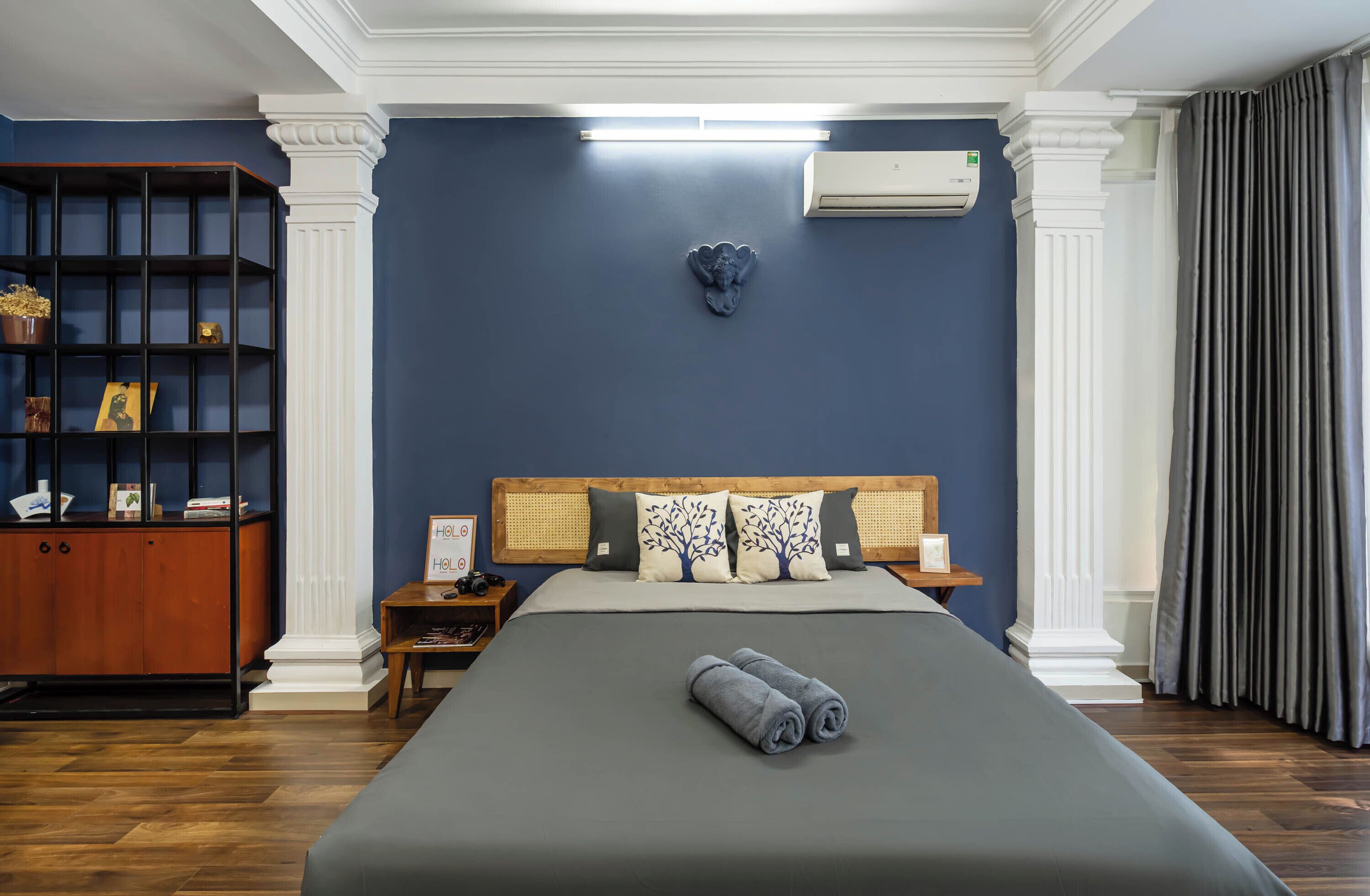 Une chambre d’hôtel avec un grand lit, une bibliothèque, un élément décoratif mural et un appareil de climatisation.