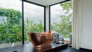A modern bathroom with a large copper bathtub, large windows, and a view of greenery. - IBU The Sanctuary by OXO - Retreat House for Family & Transformational Events (Ubud)
