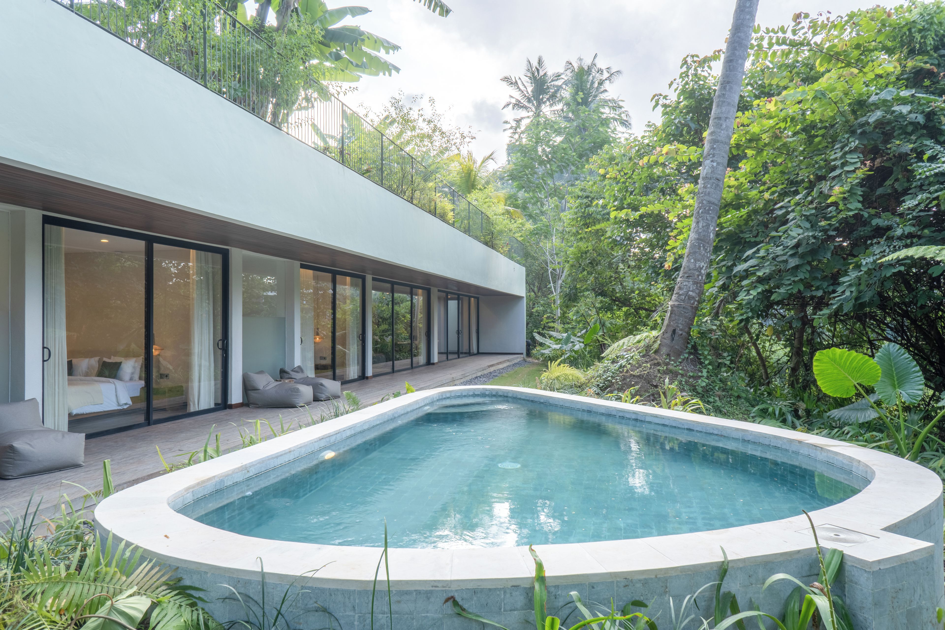 Ein modernes Haus mit Swimmingpool, großen Glasfenstern und einem Garten.
