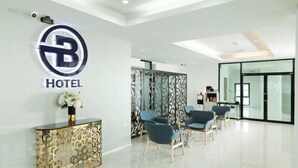 Un'accogliente area reception di un hotel moderno, con un logo, un consolle decorativo e posti a sedere.