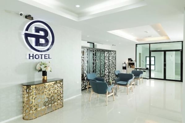 Un área de recepción de hotel moderna con un logotipo, una consola decorativa y asientos.