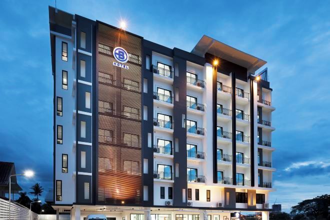 A multi-story hotel with a modern design, featuring balconies on each floor and a prominent logo on the facade.