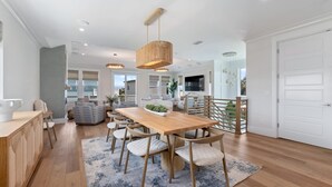 A modern kitchen with a wooden table, chairs, and pendant lighting. - E Komo Mai - Pool, Elevator, Roof Deck Views (St. Augustine)