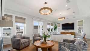 A spacious living room with a large TV, multiple seating areas, and a central coffee table. - E Komo Mai - Pool, Elevator, Roof Deck Views (St. Augustine)