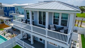 A two-story house with a balcony, a pool, and a well-maintained lawn. - E Komo Mai - Pool, Elevator, Roof Deck Views (St. Augustine)