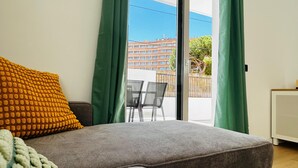 Een moderne woonkamer met een grijze bank, een geel gebreid kussen, en een witte, geweven plaid.