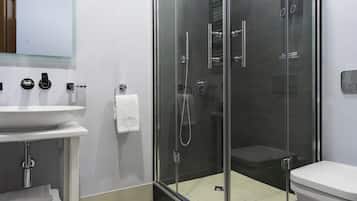 A modern bathroom with a glass-enclosed shower, a white sink, and a toilet.