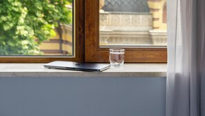 A window with a laptop and a glass of water on the sill, overlooking a building with domed architecture and a tree in the foreground. - Alma Boutique Hotel (Tbilisi)