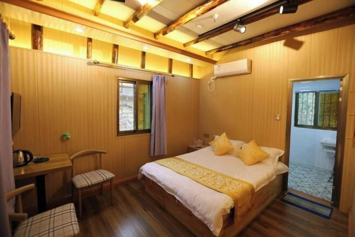 A wooden-paneled room with a bed, a desk, and a chair.